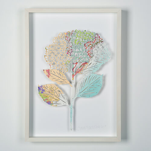 Hydrangea - Geological by Claire Brewster. A framed paper sculpture of a hydrangea flower hand-cut from a vintage geological map featuring pastel apricot and mint green tones.